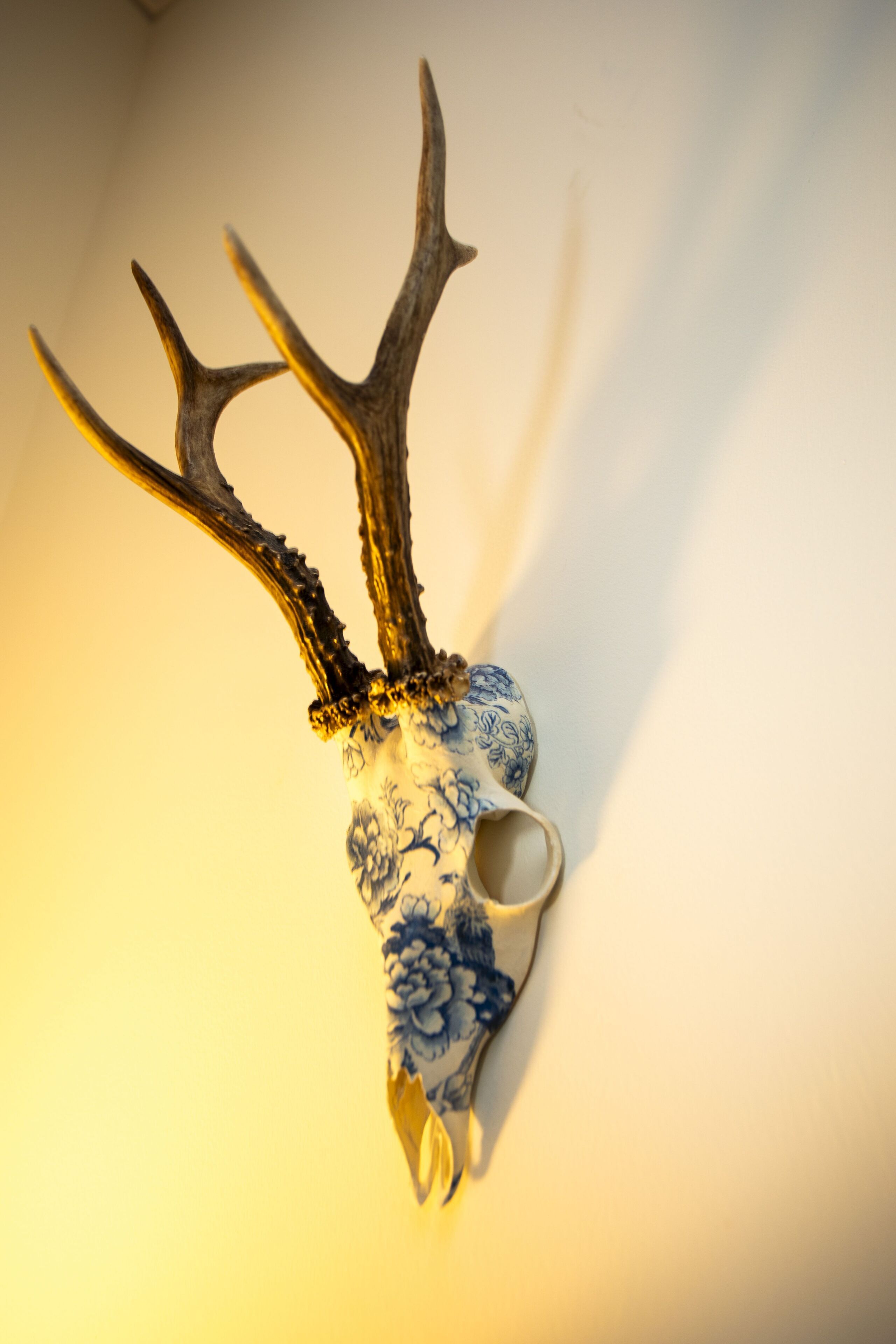 A decorative deer head mounted on a wall with a blue and white floral pattern.