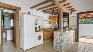 A kitchen with a washing machine, wooden cabinets, and a stone island. - Casa Marilo country house with pool in Conil de la Frontera (Conil de la Frontera)