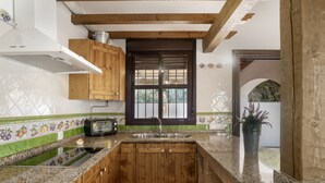 A kitchen with wooden cabinets, a built-in stove, a window, and a sink. - Casa Marilo country house with pool in Conil de la Frontera (Conil de la Frontera)