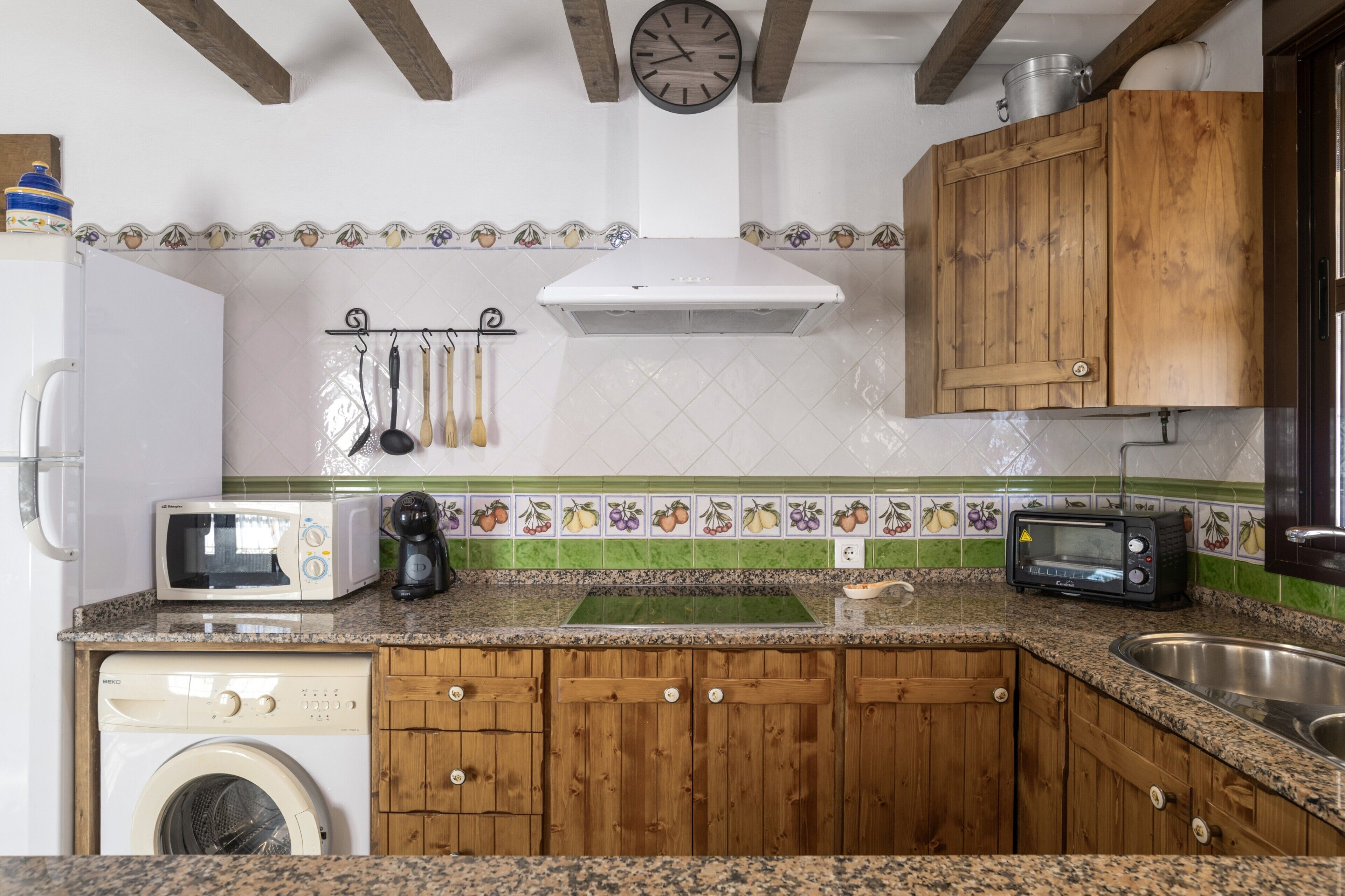 A kitchen with wooden cabinets, a microwave, a toaster, and a washing machine.