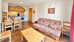 A cozy living room with a sofa, a wooden coffee table, and a dining area with a table and chairs.