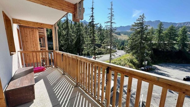 A wooden balcony with a view of a mountainous landscape.