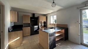 Une cuisine moderne avec des meubles en bois, un plan de travail noir et un four encastré.