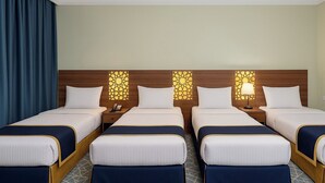 A hotel room with four beds, each with a wooden headboard and a decorative light panel. - Al Hashmeih Tower Hotel Makkah (Makkah)