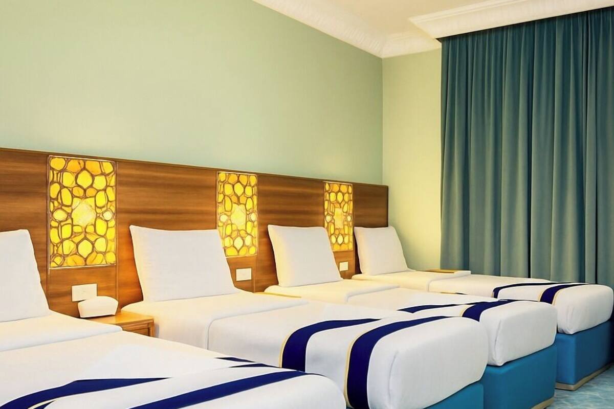 A hotel room with four beds arranged in a row, a large window with a view, and a ceiling light.