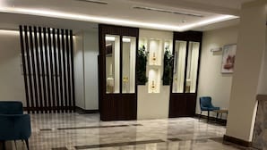 A spacious lobby with a polished marble floor, a wooden partition, and two blue chairs. - Al Hashmeih Tower Hotel Makkah (Makkah)