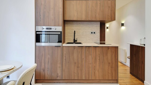 Una cocina moderna con muebles de madera, horno empotrado y un lavabo.
