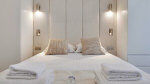 Una habitación de hotel moderna con una cama grande, dos mesitas de noche y un cabecero con iluminación integrada.