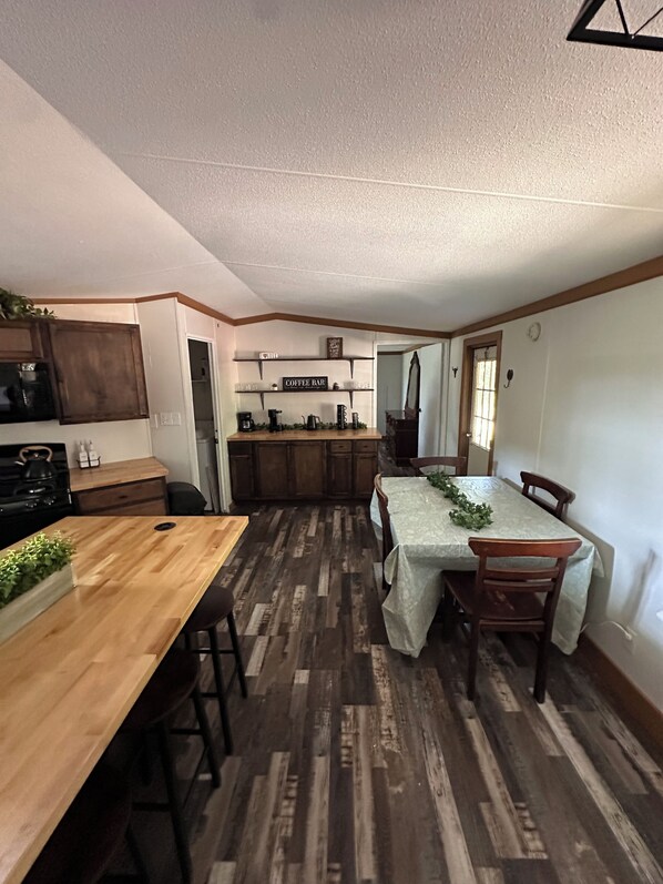 Une cuisine compacte avec des meubles en bois, un coin café et un espace repas comprenant une table et des chaises.