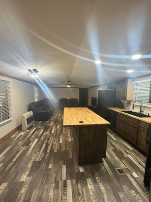 Une cuisine spacieuse dotée d’un îlot central, de planchers en bois et d’un ventilateur de plafond.