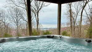Banheira de hidromassagem com vista para árvores e uma ponte ao fundo.