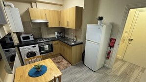 A compact kitchen with wooden cabinets, a microwave, a stove, a sink, and a refrigerator.