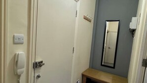 A hallway with a door, a coat hook, a mirror, and a bench.