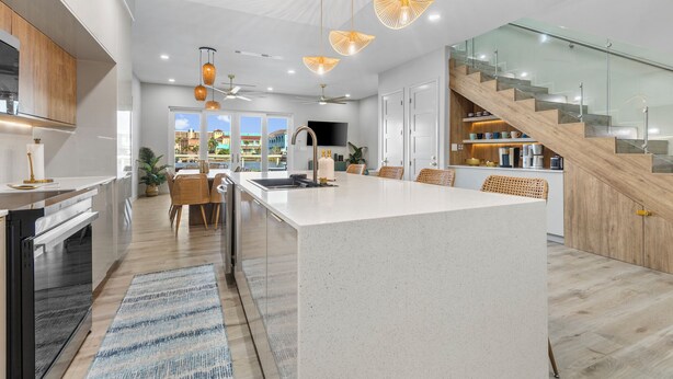 Una cocina moderna con una isla central, armarios de madera y una escalera de cristal.