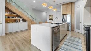 Una cocina moderna con una isla central, electrodomésticos de acero inoxidable y una escalera de madera.