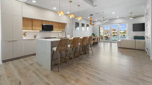 Una cocina moderna con una isla central, taburetes de bar e iluminación colgante.