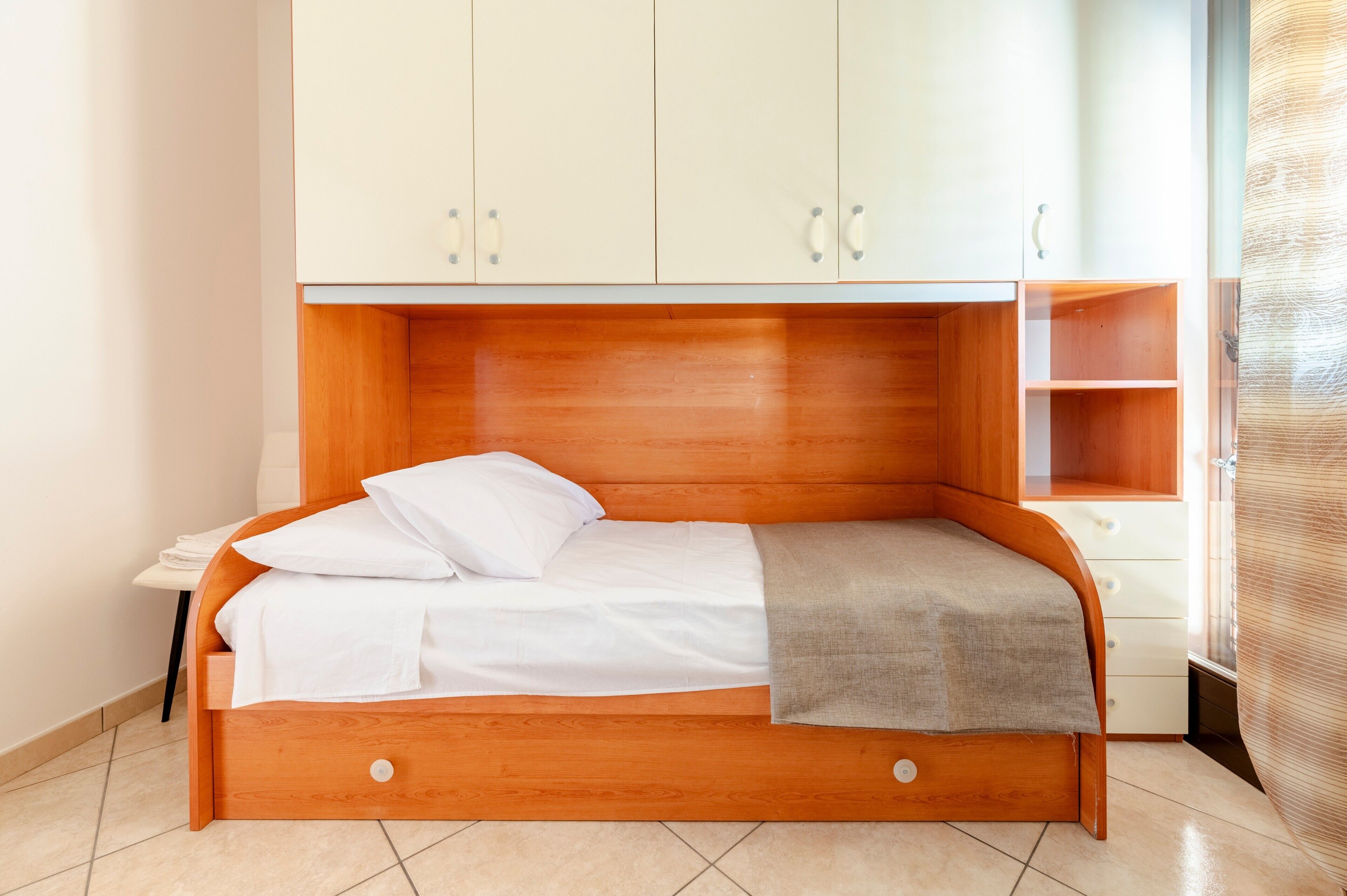 A single bed with a wooden headboard, white bedding, and a small bedside table.