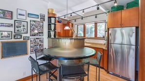 A modern kitchen with a central island, stainless steel appliances, and a variety of framed photos on the walls.