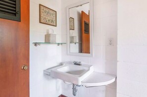 A bathroom with a white sink, a mirror, and a wooden door. - Charming Mid - Century home in the lovely Palisades Park gated community. (Covert)