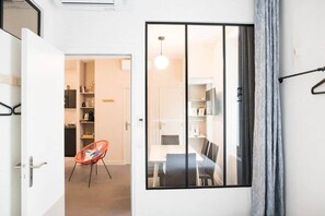 A modern room with a sliding glass door leading to a dining area, a red chair, and a hanging light fixture. - Family friendly apartment in the heart of Paris (Paris)