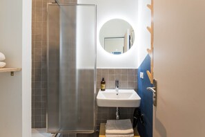 Un baño con ducha, lavabo y espejo.