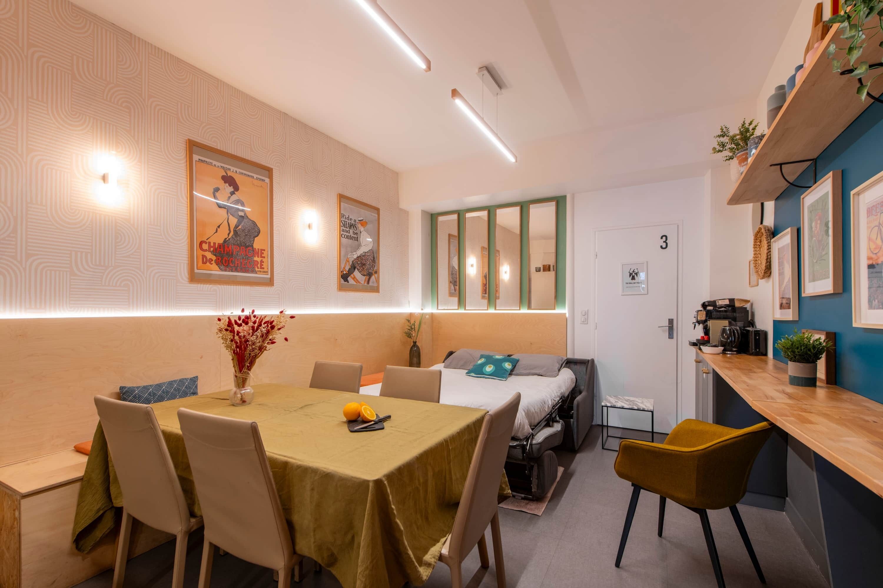 A compact living space with a dining area, kitchenette, and a bed.