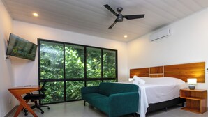 Una habitación de hotel moderna con un ventanal grande, una cama, un escritorio y un televisor.