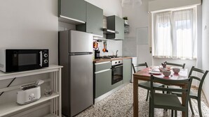 A compact kitchen with a microwave, stove, oven, and a dining area with a table and chairs. - GuestHost - Cozy 75 sqm apartment, perfect for four people, located on the fourth floor of a building with an elevator (NOT wheelchair accessible).The property is located in a well-served residential neighborhood, just a short public transportation ride  (La Spezia)