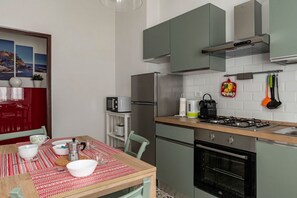 A modern kitchen with a dining area, stainless steel appliances, and a red and white patterned tablecloth.