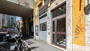 A street view with a closed shop, a parked scooter, and a building with graffiti. - GuestHost - Cozy 75 sqm apartment, perfect for four people, located on the fourth floor of a building with an elevator (NOT wheelchair accessible).The property is located in a well-served residential neighborhood, just a short public transportation ride  (La Spezia)