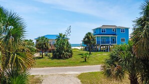 A coastal property with two blue houses, a gravel driveway, and palm trees. - Papa's Palmetto Place (Port St. Joe)
