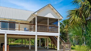 A two-story building with a covered porch and a staircase leading to the upper level. - Papa's Palmetto Place (Port St. Joe)