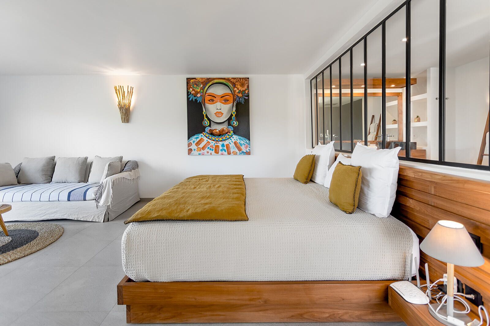 Una camera da letto moderna con un letto grande, un divano e un quadro appeso al muro.