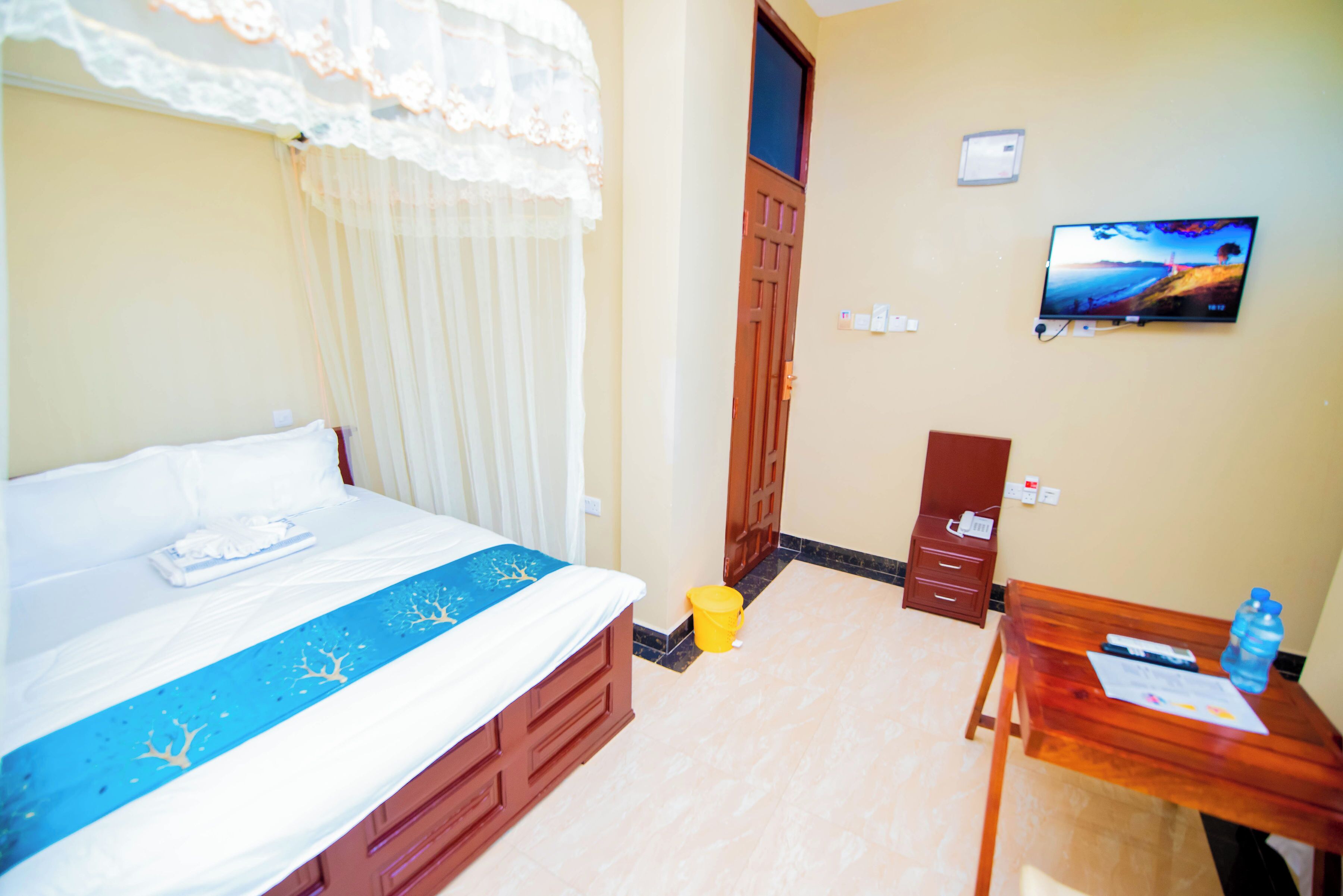 A hotel room with a bed, a desk, a television, and a door.