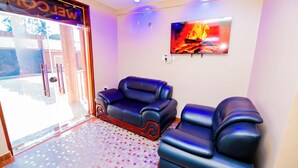 A room with a sofa and a massage chair, a TV mounted on the wall, and a patterned floor. - HBE HOTEL KIGAMBONI (Dar es Salaam)