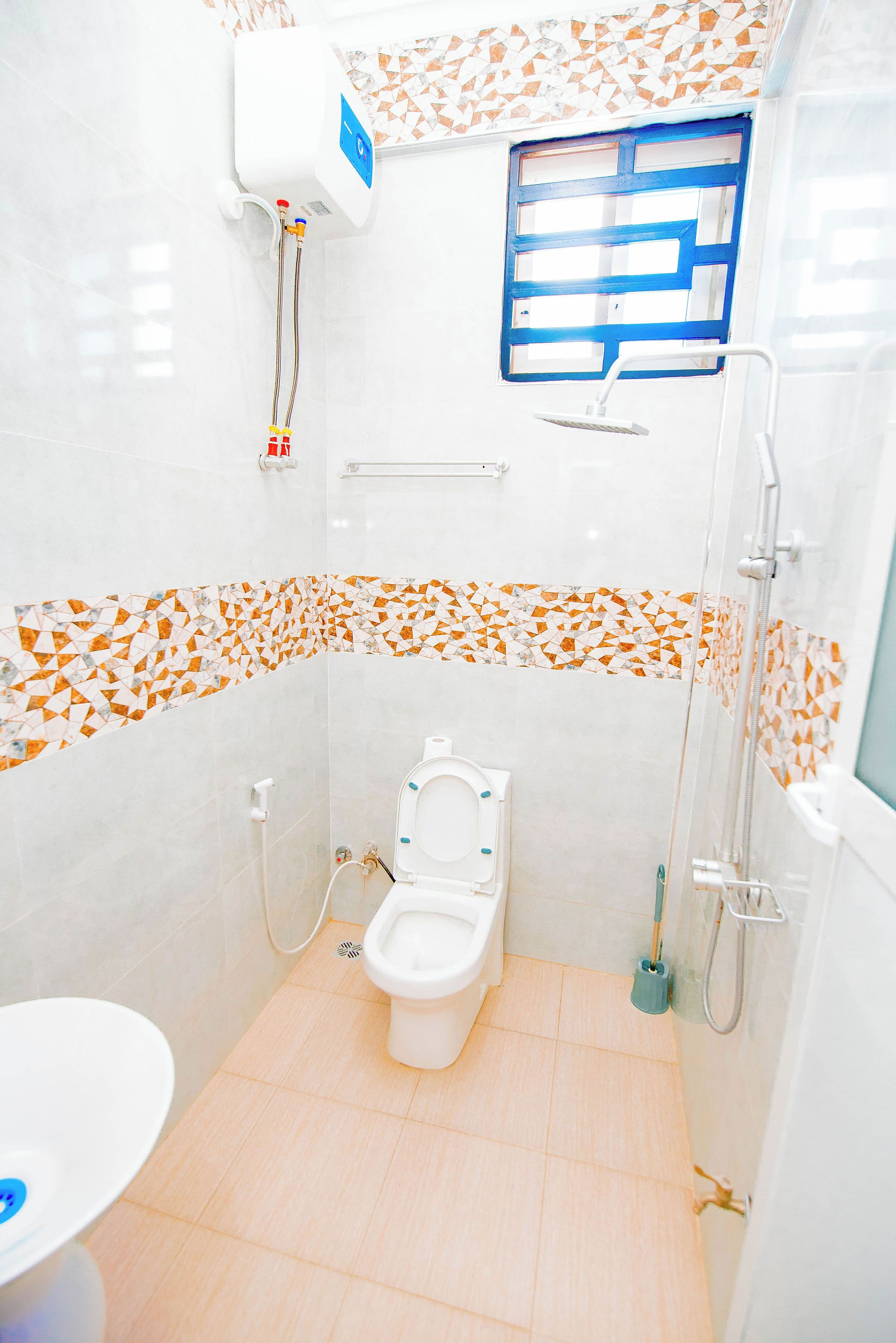 Une petite salle de bain moderne, équipée de toilettes, d’une douche et d’un lavabo.