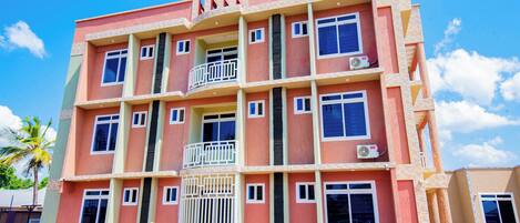 Un motel de varios pisos con balcones y unidades de aire acondicionado.