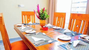 A dining table set with placemats, plates, cutlery, and a potted plant.