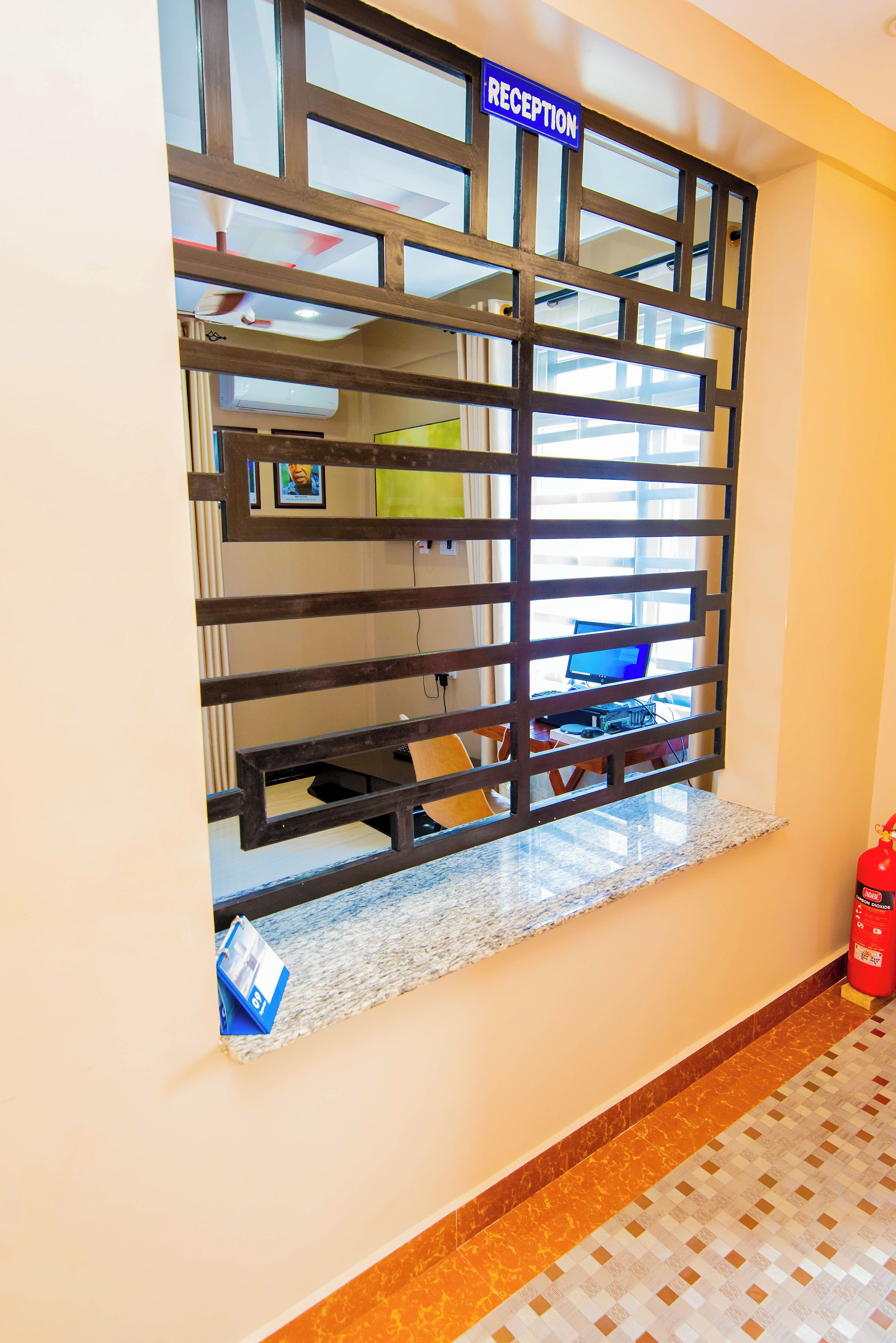 A reception area with a 'RECEPTION' sign, a computer desk, a fire extinguisher, and a patterned floor.