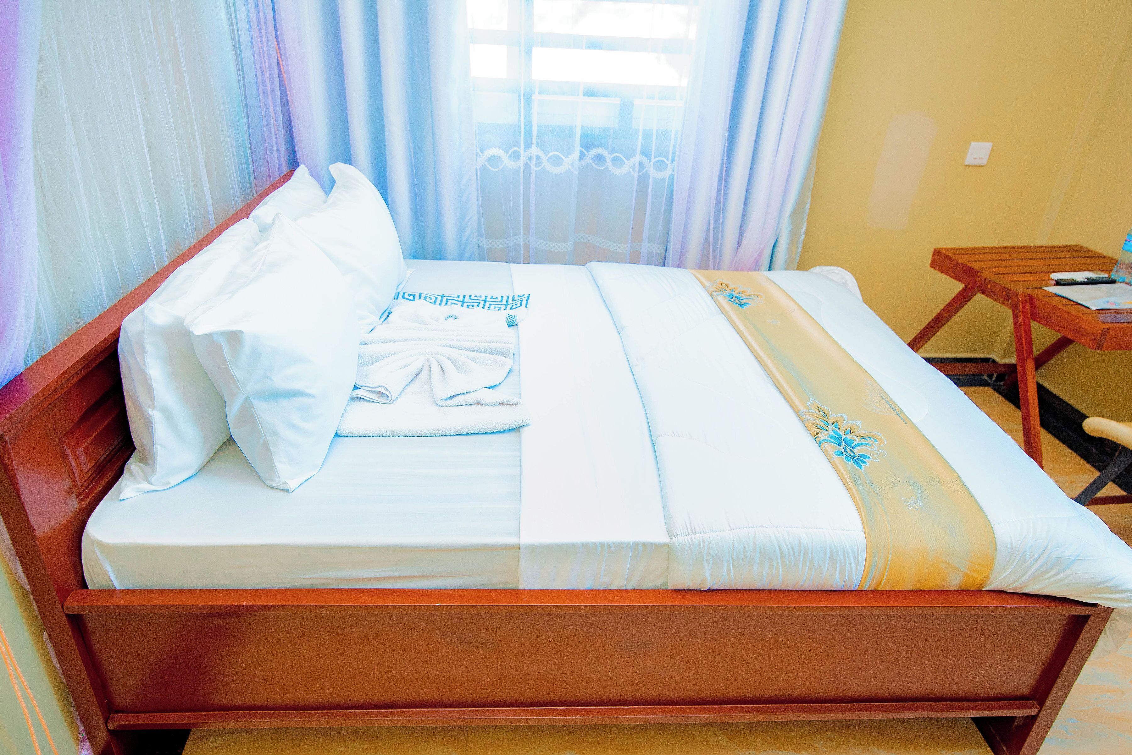 A neatly made bed with white linens and a decorative pillow.
