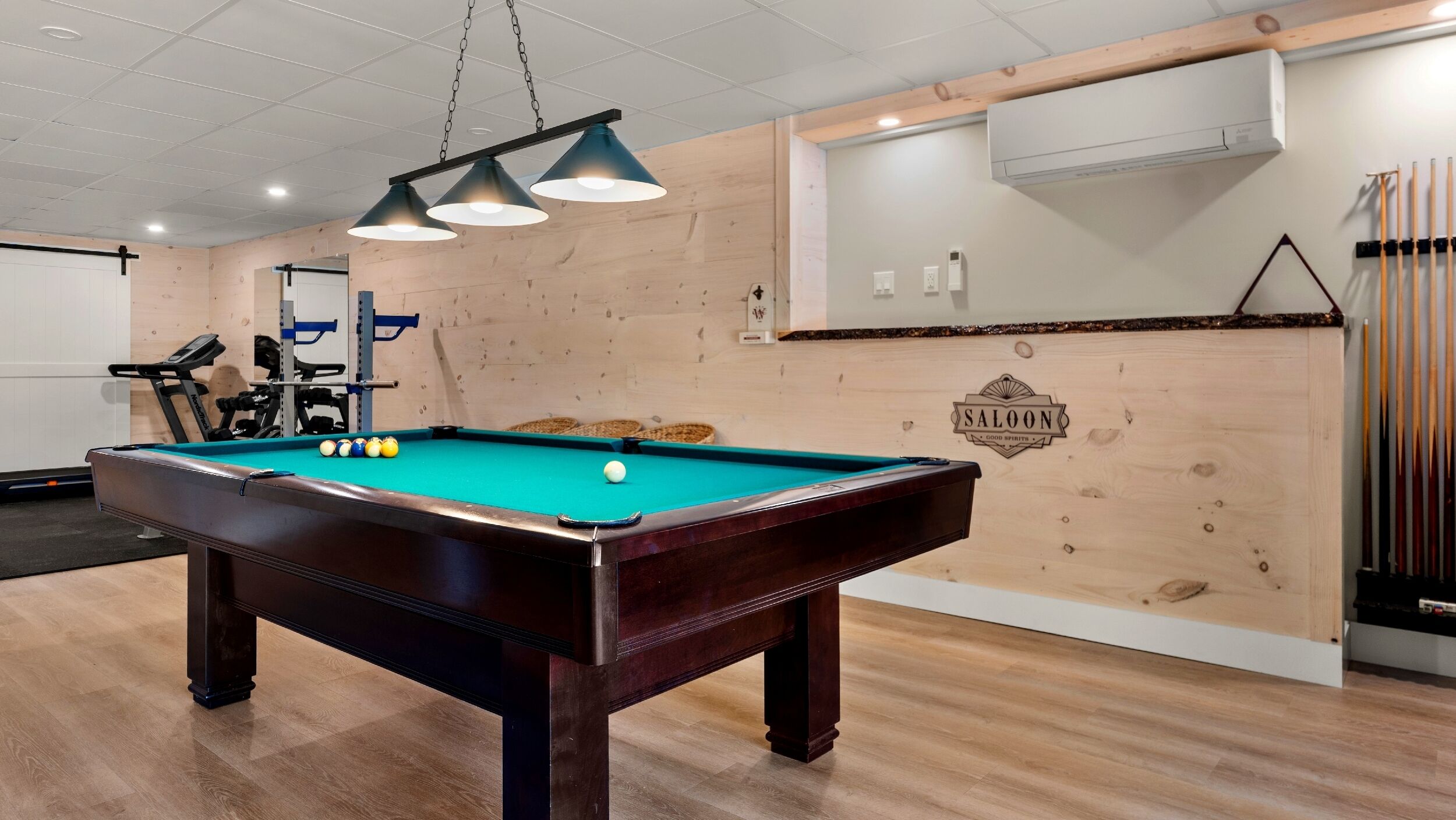 A pool table in a room with wooden walls and a ceiling with recessed lighting.