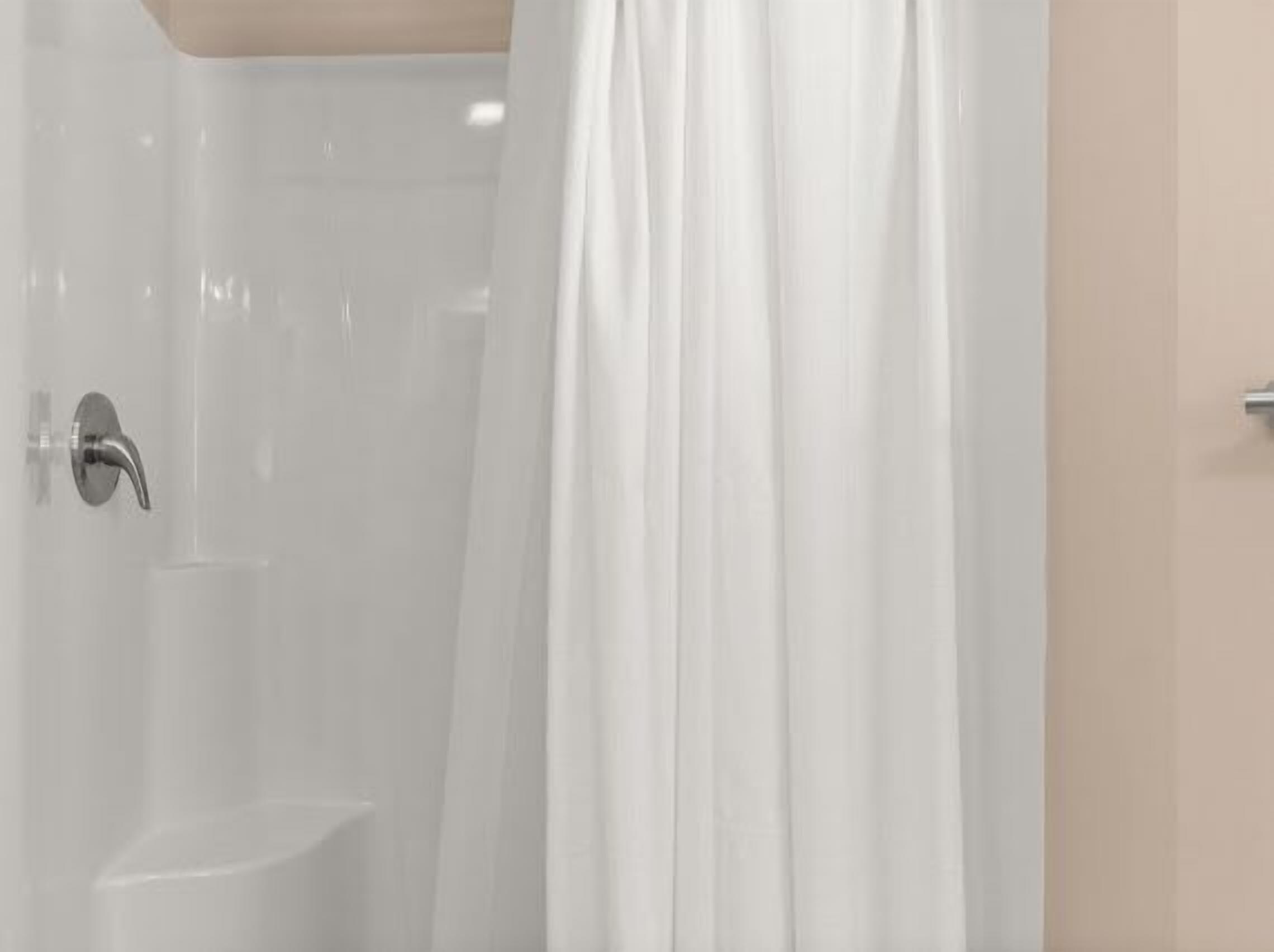 Ein Badezimmer mit einer weißen Badewanne, einer Duschvorhang und einem Wandarmaturen.