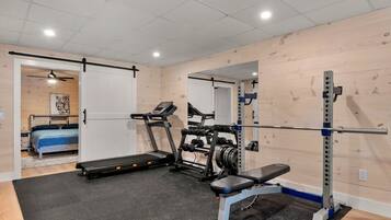 Een sportschool met een loopband, een gewichtbank en een squats rek.