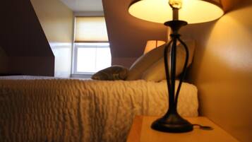 Un dormitorio con cama, lámpara y ventana.
