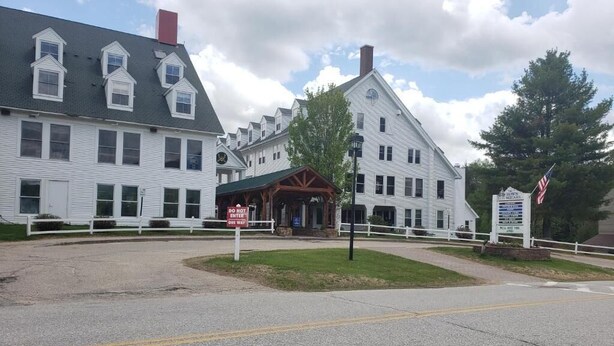 A historic building with a prominent entrance, a sign indicating a 'Do Not Enter' for the main road, and an American flag.