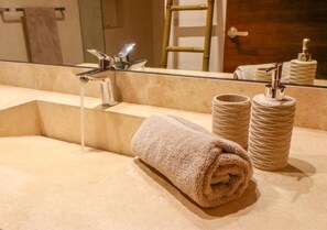A bathroom with a beige sink, a towel, and a mirror reflecting a towel and a bamboo ladder. - Tulum 2 recámaras con alberca privada (Tulum)