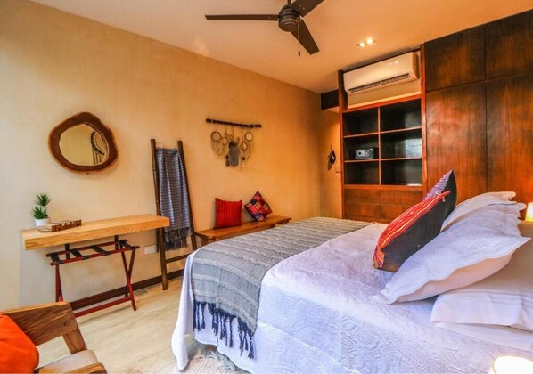 A bedroom with a bed, a desk, a chair, a ceiling fan, and a wardrobe.