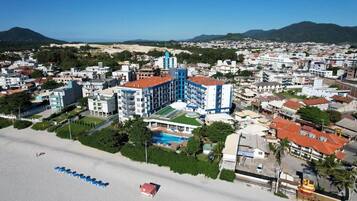 A coastal hotel with multiple buildings, a beach, and a mountain in the background.