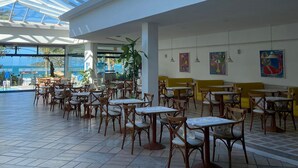 A spacious indoor area with a high ceiling and large windows, featuring multiple tables and chairs arranged for dining or socializing. - Ingleses Praia Hotel (Florianópolis)