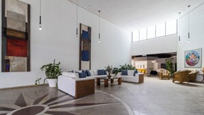 A spacious lobby with a modern design, featuring a large sun-shaped floor pattern, white sofas with blue accents, and hanging pendant lights. - Ingleses Praia Hotel (Florianópolis)